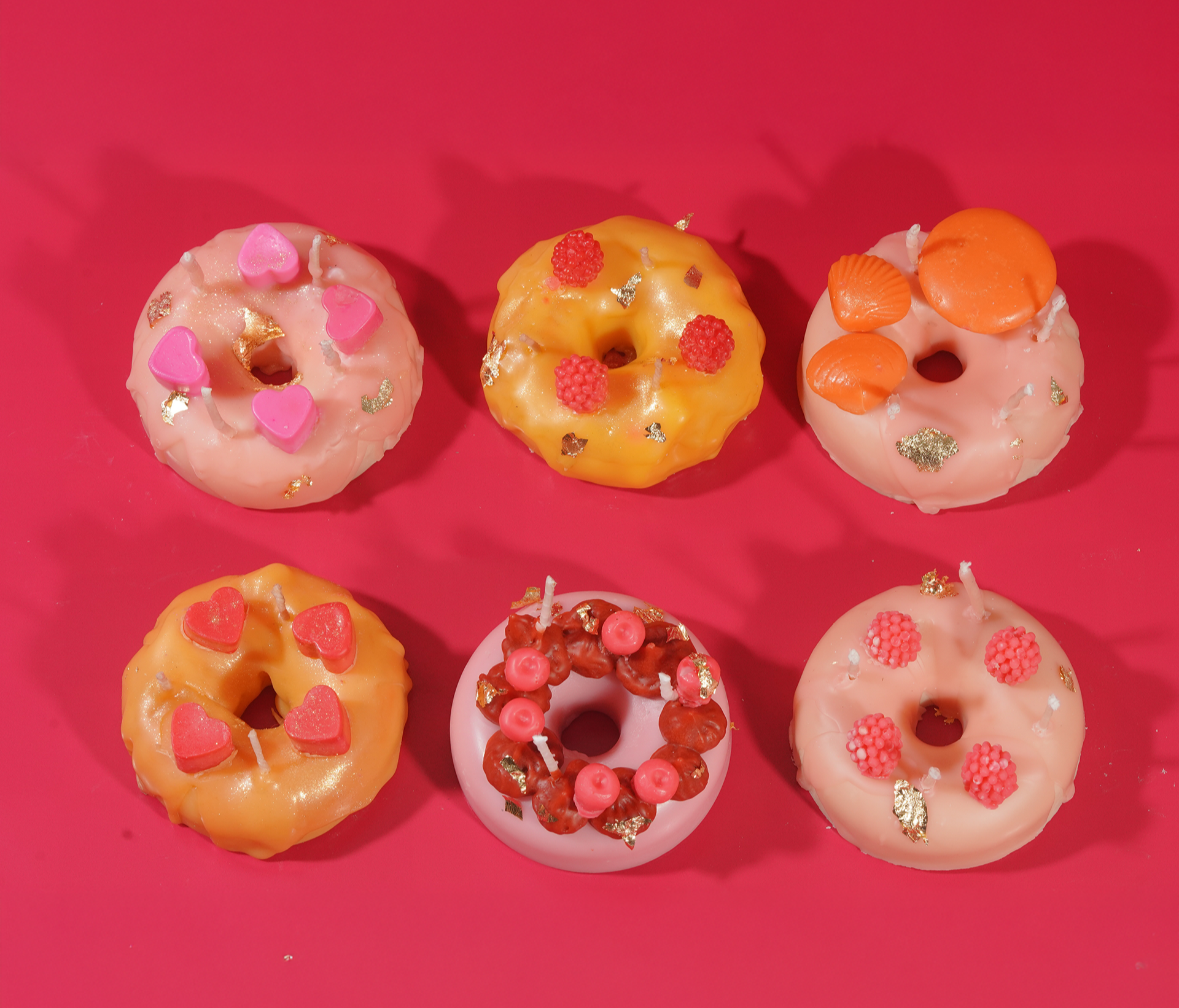 Donut-shaped candles made by saga studio with decorative elements on a pink background
