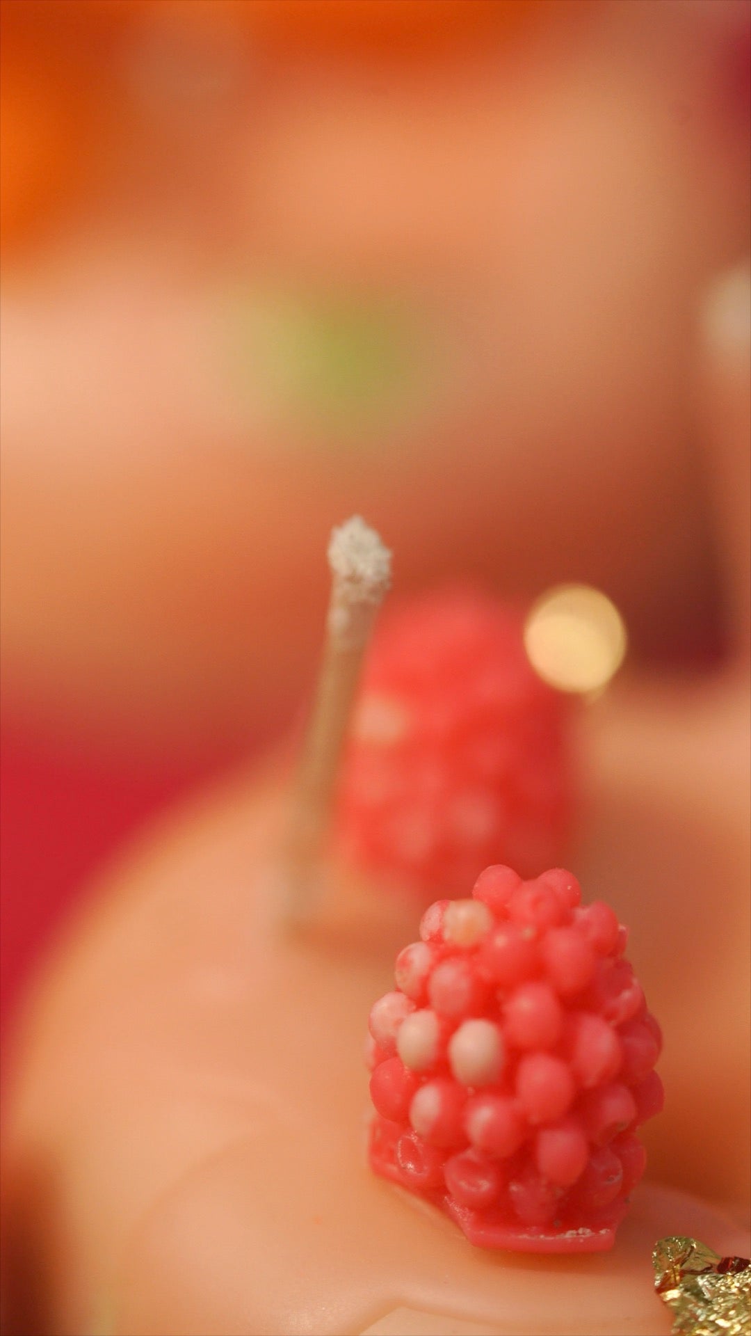 Close-up of a small red berry of a donut dessert candle made by saga studio